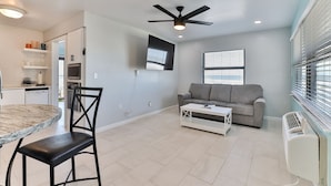 A modern living room with a grey sofa, a white coffee table, and a ceiling fan.
