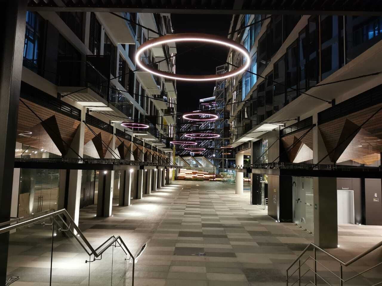Un intérieur moderne avec un escalier central, de nombreux étages et des luminaires de forme circulaire.