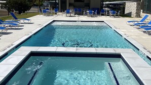 A rectangular pool with clear blue water, surrounded by blue lounge chairs and a covered seating area. - Harborview FIRST FLOOR Condo w/ resort amenities easy poolside access w/ views! (Graford)