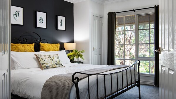 A bedroom with a bed, a nightstand, a lamp, and a window with curtains.