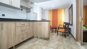 A modern kitchen with wooden cabinets, a granite countertop, and a dining area with two chairs. - Hotel Ayenda Olimpa 1144 (Pereira)