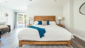 A bedroom with a wooden bed, two bedside lamps, a ceiling fan, and a view of the outdoors through a sliding glass door. - Family Friendly Golf Pool & Games Getaway 4 beds #067932 (La Quinta)