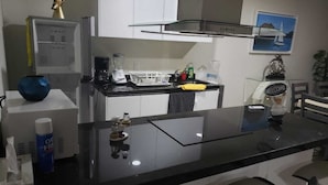 Een moderne keuken met witte kasten, een zwart aanrecht en een koffieapparaat.
