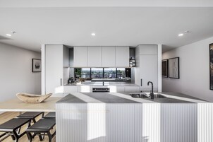Cocina moderna con una isla central, electrodomésticos integrados y un amplio ventanal con vistas a la ciudad.