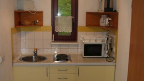 Een kleine keuken met een spoelbak, magnetron en houten planken.