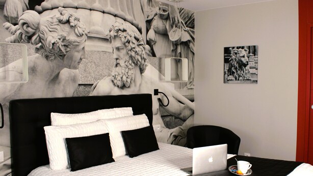 A bedroom with a bed, a laptop, a cup, and a wall mural. - Les Béthunoises Béthune Centre (Béthune)