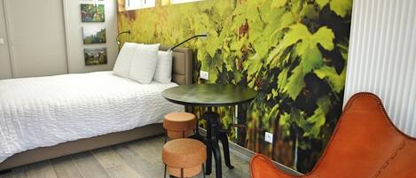A bedroom with a bed, a round table, two stools, and a chair.