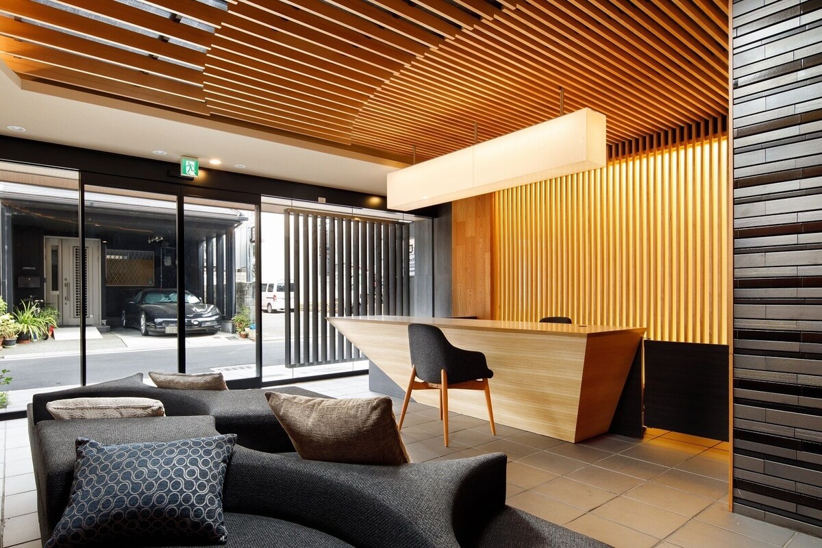 A modern reception area with a wooden slatted ceiling, a reception desk, and a seating area with patterned cushions.