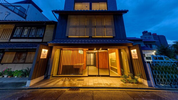 A modern two-story hotel with a traditional Japanese entrance, large windows, and a well-lit facade. - Connect inn Shichijokawaramachi (Kyoto)