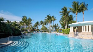 Ein Pool, umgeben von Palmen und einem Gebäude mit Säulen.