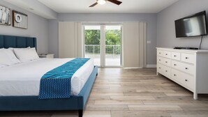 Une chambre avec un lit, une télévision, une commode et un balcon offrant une vue.