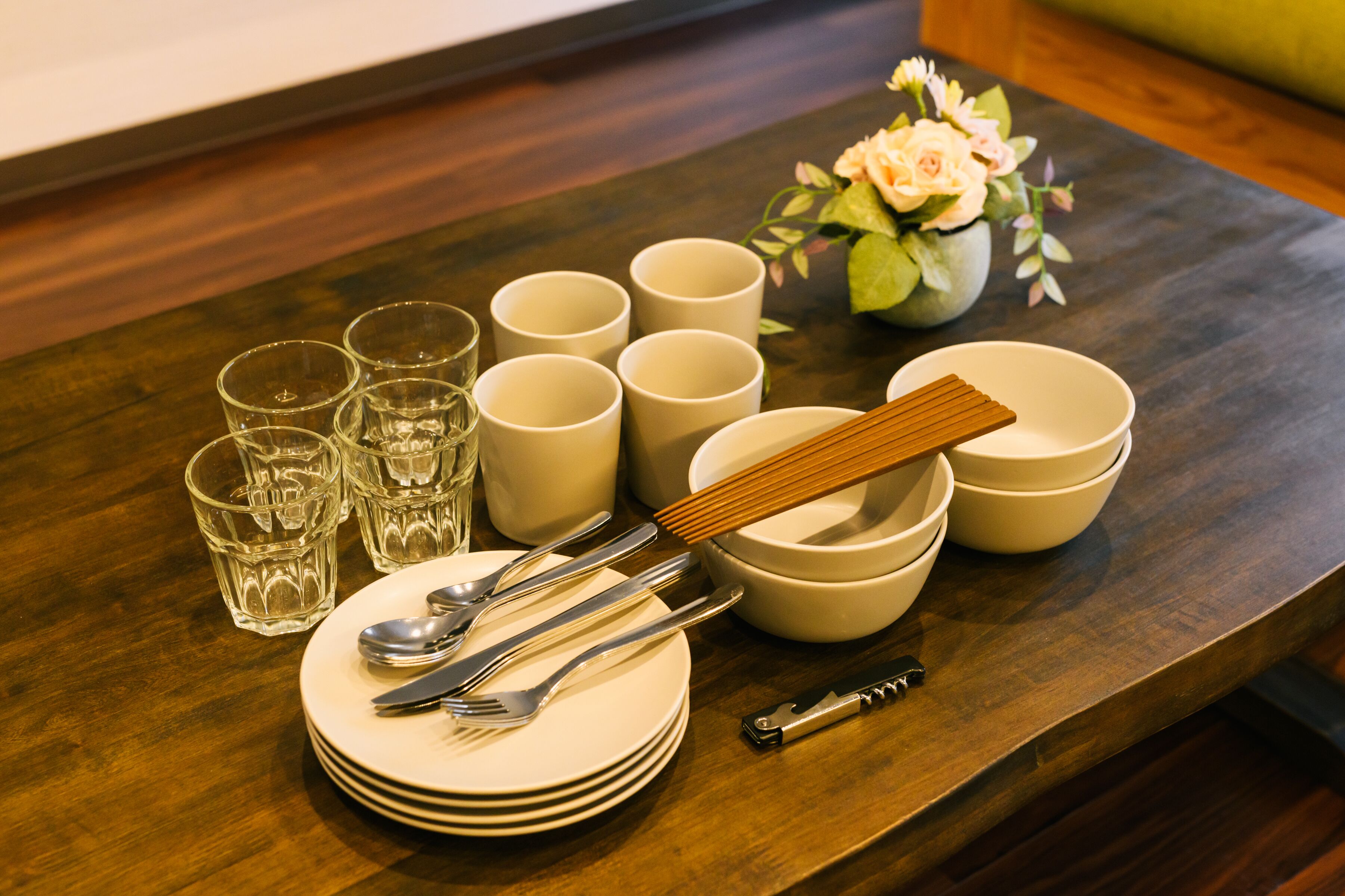 A neatly arranged dining table with plates, cutlery, glasses, and bowls.
