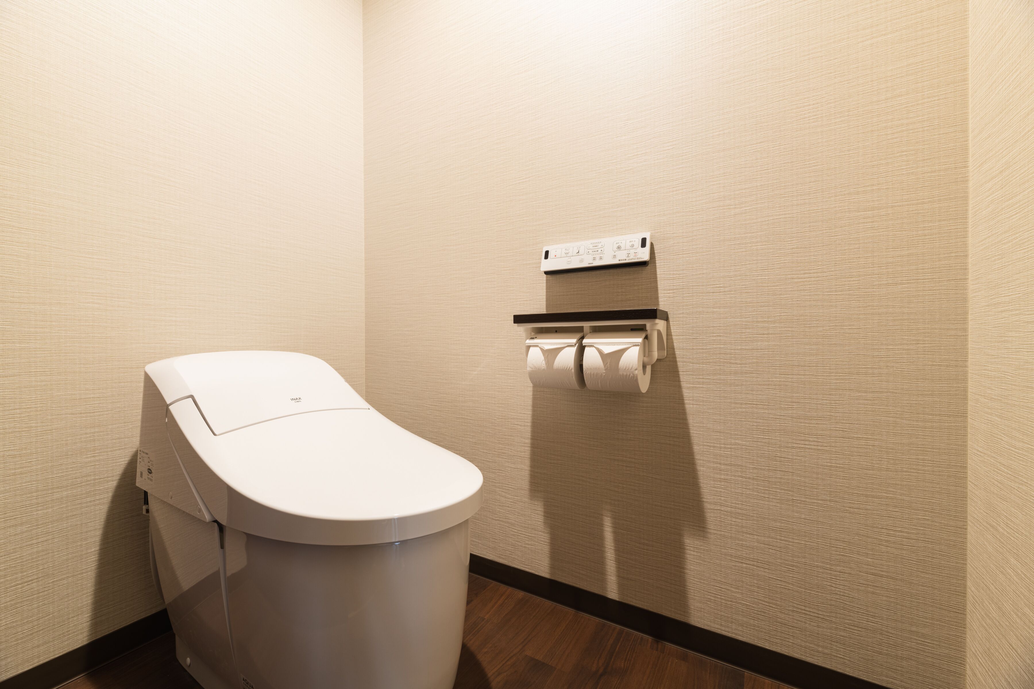 A modern bathroom with a white toilet, a paper towel dispenser, and a wall-mounted paper towel holder.