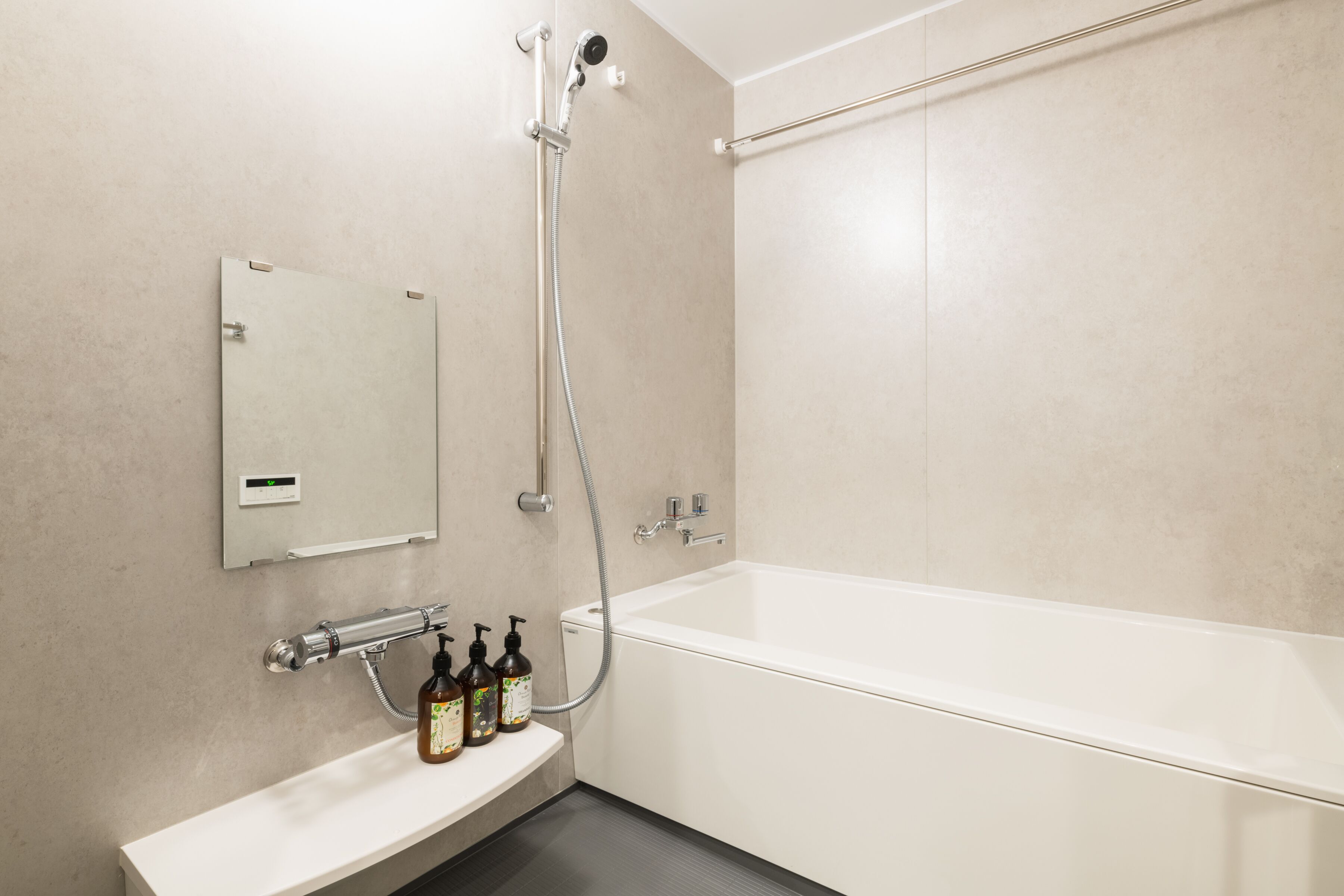 A modern bathroom with a white bathtub, a handheld showerhead, and a wall-mounted mirror.