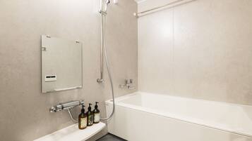 A modern bathroom with a white bathtub, a handheld showerhead, and a wall-mounted mirror.