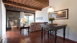 A rustic interior with a wooden ceiling, a stone wall, a dining table with chairs, a sofa, and a lamp. - Casa Ruta A: A characteristic and welcoming apartment surrounded by the greenery, with Free WI-FI. (Monterotondo marittimo)