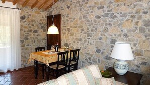 A dining area with a stone wall, wooden ceiling, and a table set for two. - Casa Ruta C: A characteristic and welcoming apartment surrounded by the greenery, with Free WI-FI. (Monterotondo marittimo)