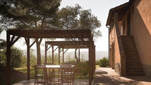 A wooden pergola with a table and chairs, overlooking a mountainous landscape.