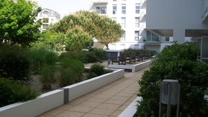 A pathway leading to outdoor seating with a view of residential buildings. - BEAUTIFUL T2 APARTMENT with secure parking, 8-minute walk to beach, ports, center,  (LES SABLES D'OLONNE)