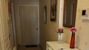 A narrow hallway with a white radiator, a door at the end, and a white cabinet with drawers. - BEAUTIFUL T2 APARTMENT with secure parking, 8-minute walk to beach, ports, center,  (LES SABLES D'OLONNE)