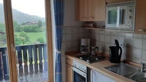 Una cocina con vistas a un paisaje verde, un microondas, una cafetera y un hervidor.