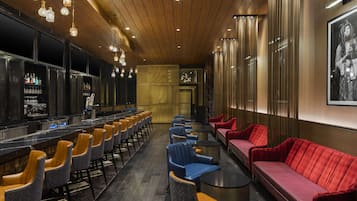 A bar area with seating, bar counter, and a large framed picture on the wall.