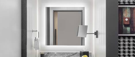 A modern bathroom with a large mirror, a marble sink, and a towel rack.