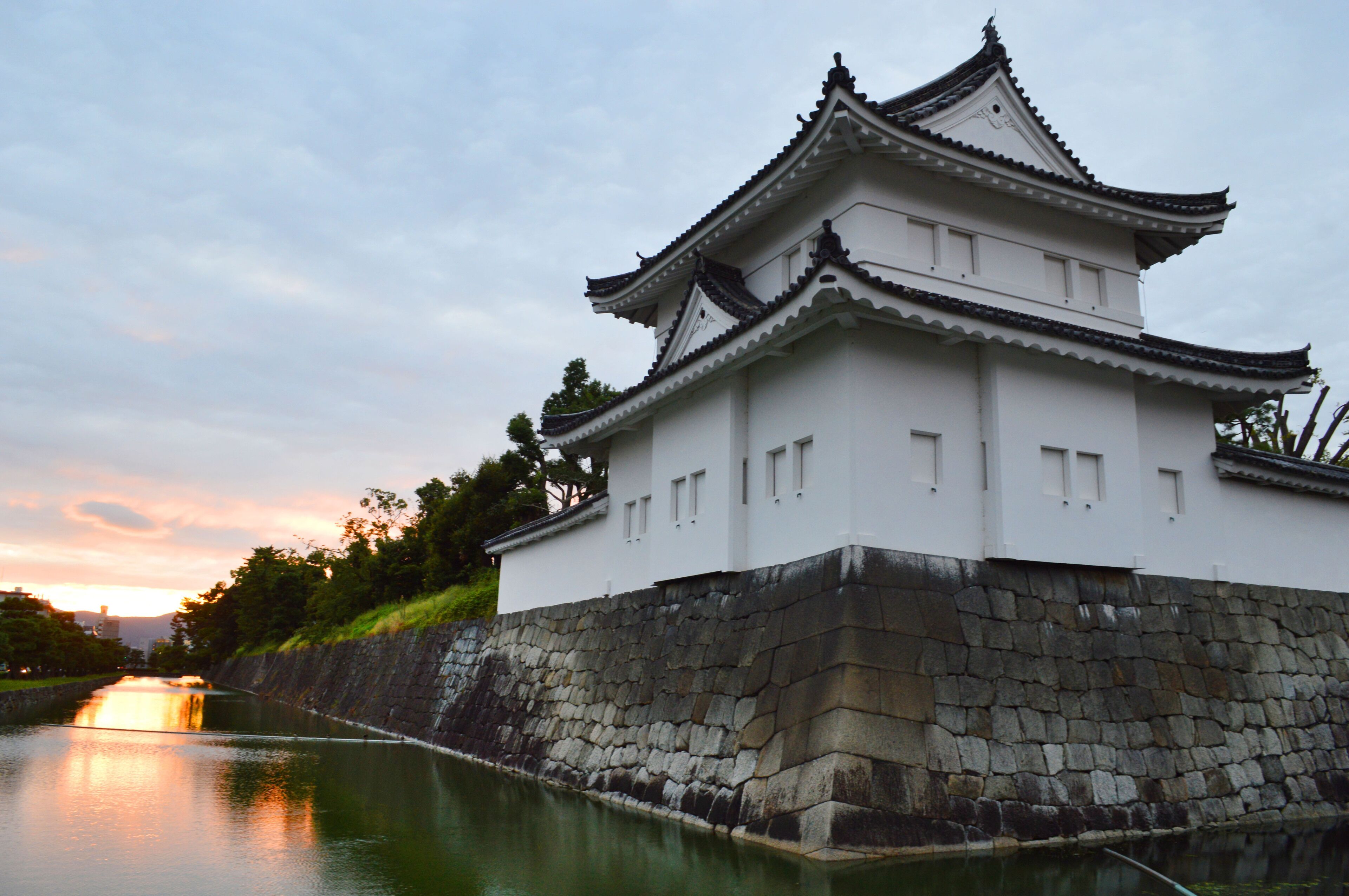 A traditional Japanese castle with a stone wall and a river in the foreground.