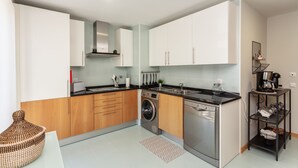 A compact kitchen with white cabinets, a washing machine, and a dishwasher.