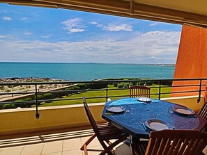 Enjoy a meal on the balcony with a view of the sea, surrounded by a round table and four chairs.