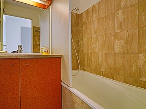 Bathroom features a bathtub, showerhead, and vanity with drawers.