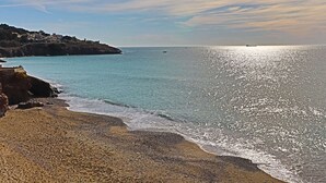 A coastal beach with a rocky shoreline, calm sea, and a distant boat. - 2⭐ Apartment with pool and parking in Sète (Sète)