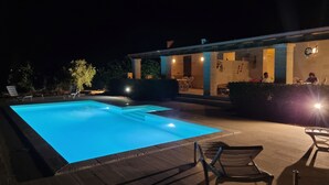 A swimming pool with a tiled deck, lounge chairs, and a building with outdoor seating and lighting. - VILLA AMICORUM House EAST, pool 10 x 4 m  (San Pietro in Bevagna)