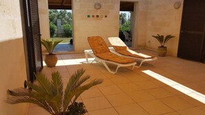 A sunlit outdoor area with two lounge chairs and a potted plant. - VILLA AMICORUM House EAST, pool 10 x 4 m  (San Pietro in Bevagna)