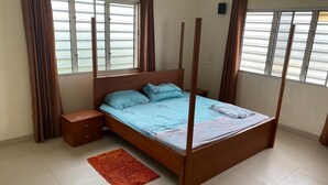 Una camera da letto con un letto a baldacchino, un comodino, un tappeto rosso e finestre con tende.