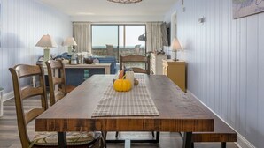 A dining area with a wooden table, chairs, and a hanging light fixture. - Direct oceanfront in convenient mid town location (Ocean City)
