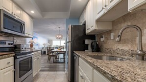 A modern kitchen with white cabinets, granite countertops, stainless steel appliances, and a central island. - Direct oceanfront in convenient mid town location (Ocean City)