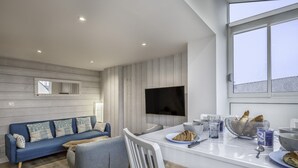 A modern living room with a blue sofa, grey armchair, and a dining area with a white table. - 600m from the beach, duplex for 4 (Sarzeau)