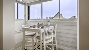 A dining area with a white table and chairs, large windows, and a view of buildings. - 600m from the beach, duplex for 4 (Sarzeau)