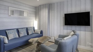 A living room with a blue sofa, grey armchairs, a wooden coffee table, and a mounted TV. - 600m from the beach, duplex for 4 (Sarzeau)
