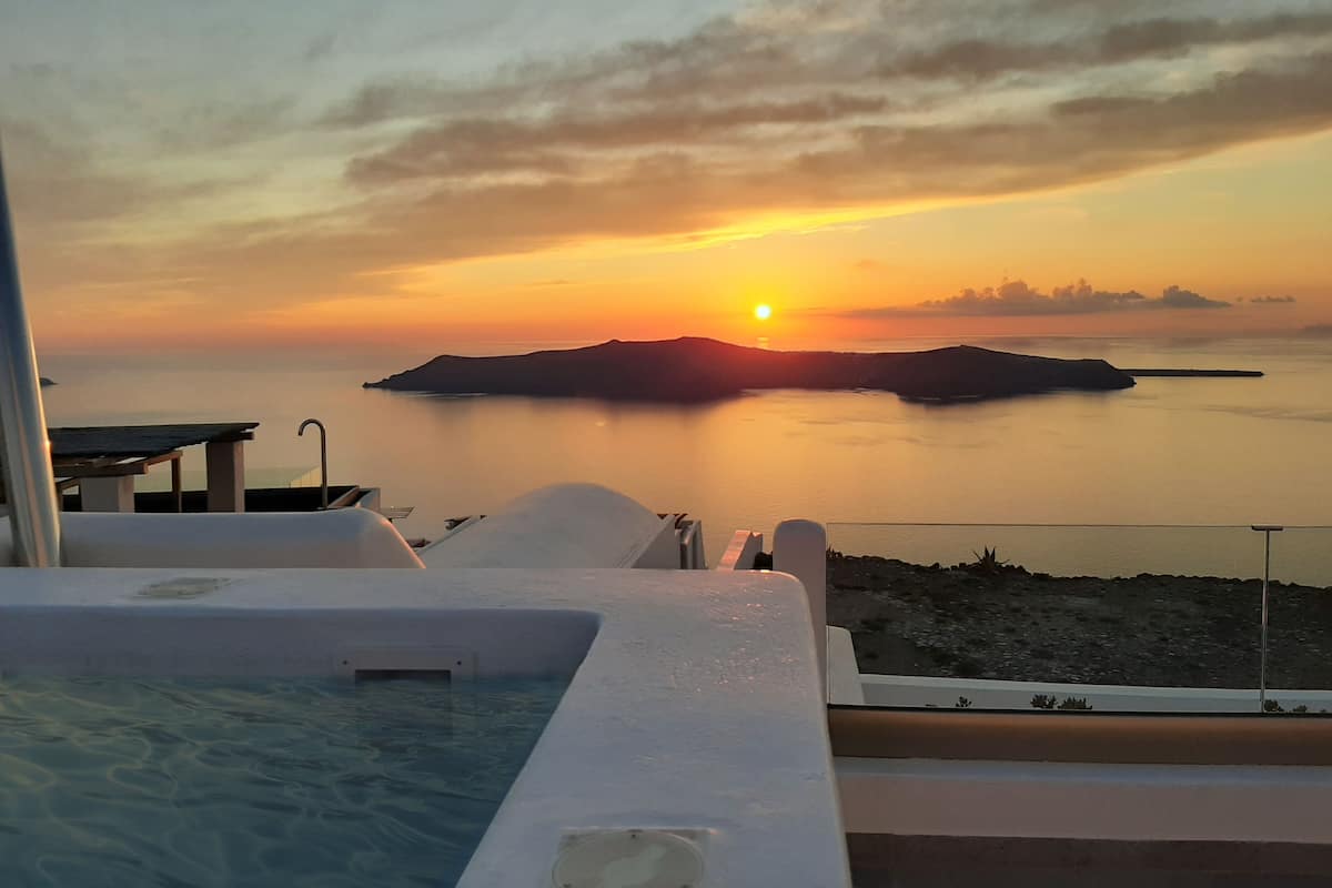 A poolside view with a sunset over water and islands.