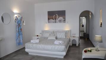 A modern bedroom with a large bed, a nightstand, a bedside table, and a wall-mounted mirror.