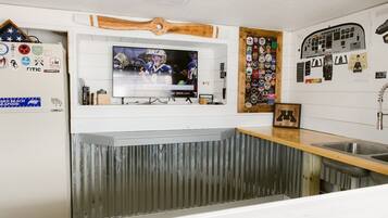 A kitchen with a TV mounted above a counter, a wooden accent wall, and various wall decorations.