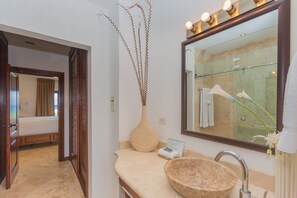 A bathroom with a large mirror, a beige sink, and a wooden bowl. - Pristine Bay 1108 4 Bedroom Home by RedAwning (Roatan)
