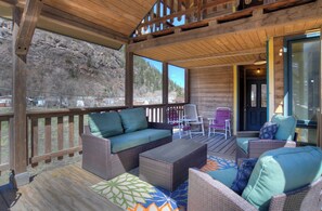 Un espacio al aire libre techado con mobiliario de mimbre y vistas a un paisaje montañoso.