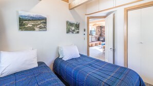 A bedroom with two beds, a wooden ceiling, and a view of a fireplace and outdoor area. - Cozy Loft Located in the Heart of Ouray | Air Conditioning! (Ouray)