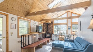 A cozy living room with a fireplace, a sofa, a TV, and a wooden ceiling. - Cozy Loft Located in the Heart of Ouray | Air Conditioning! (Ouray)