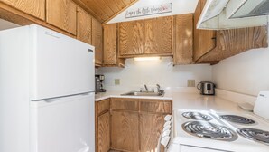A compact kitchen with wooden cabinets, a white refrigerator, a stove, and a coffee maker. - Cozy Loft Located in the Heart of Ouray | Air Conditioning! (Ouray)