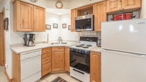 A kitchen with wooden cabinets, a stainless steel microwave, a white refrigerator, and a stove.