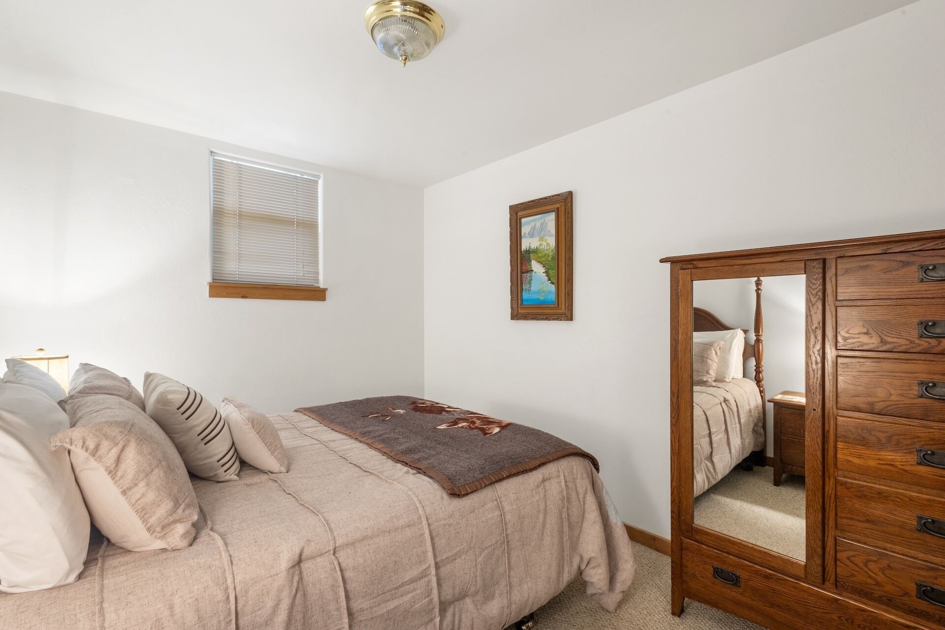 Ein Schlafzimmer mit einem Bett, einem Schminktisch, einem Fenster mit Jalousien und einem Bild an der Wand.